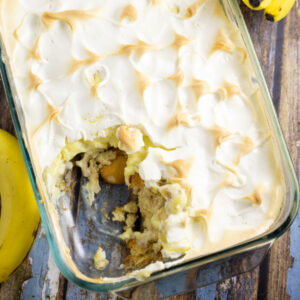 Overhead picture of southern banana pudding topped with meringue next to a banana on a rustic wood background
