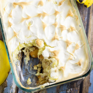 Overhead picture of southern banana pudding topped with meringue next to a banana on a rustic wood background
