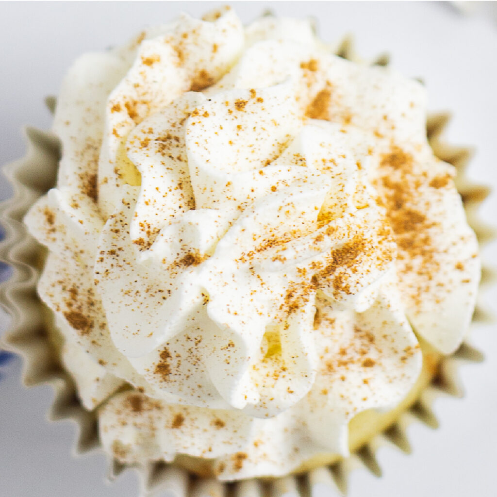 Overhead picture of a cupcake topped with Whipped Mascarpone Frosting and a sprinkle of cinnamon