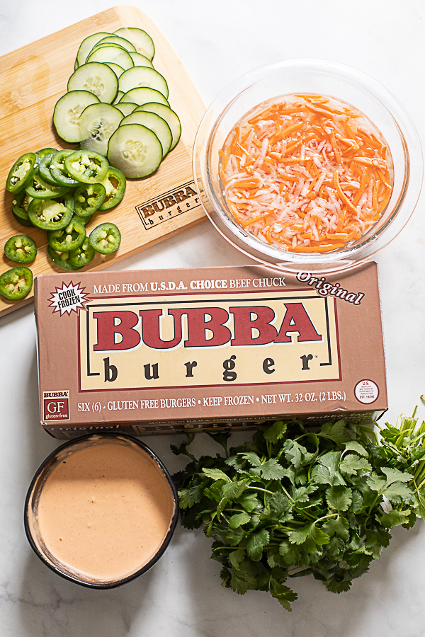 Photo of the ingredients used to make banh mi burgers, including BUBBA burgers, cucumber slices, jalapeno slices, spicy mayo, pickled carrot and daikon, and fresh cilantro.