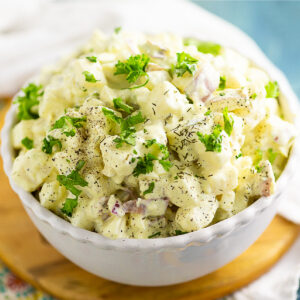 Overhead view of a small bowl of southern potato salad topped with fresh parsley and dill.