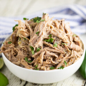 A bowl filled with slow cooker Chipotle carnitas, topped with chopped fresh cilantro