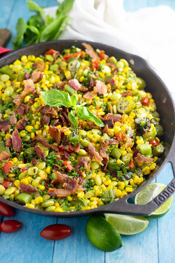 Southern succotash in a cast iron skillet topped with bacon and fresh basil
