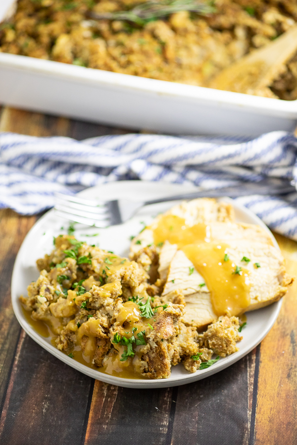 Traditional Thanksgiving Stuffing on a small plate with turkey topped with gravy.