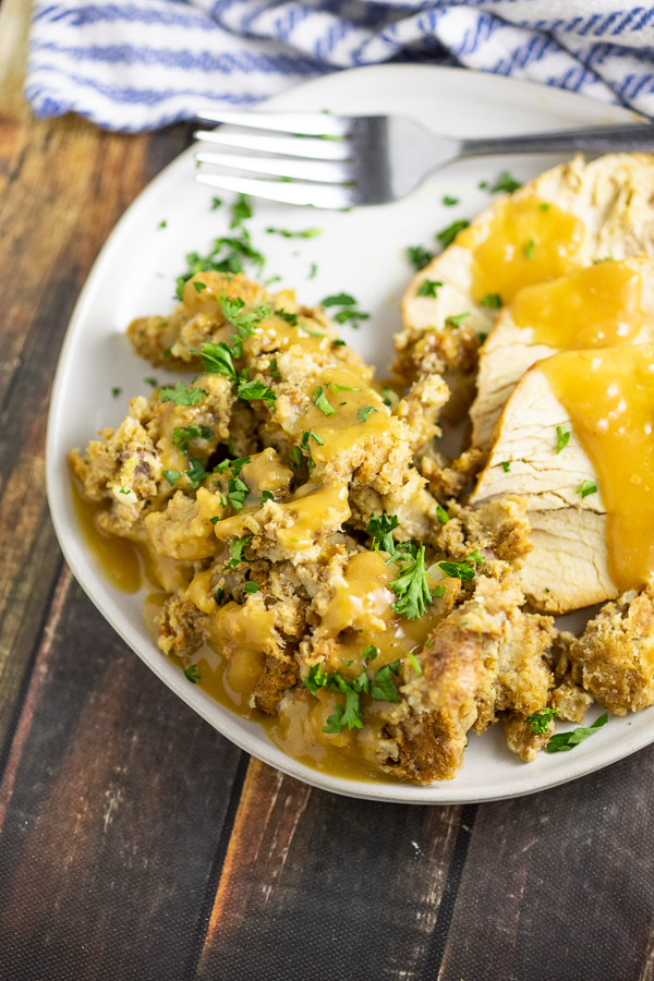 Close up of traditional Thanksgiving stuffing topped with gravy next to turkey