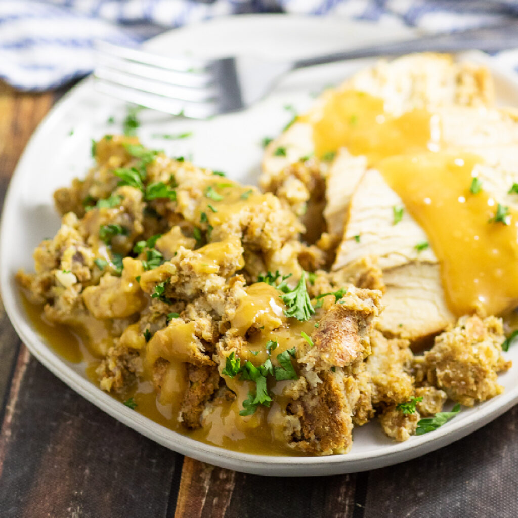 Traditional Thanksgiving Stuffing on a small plate with turkey topped with gravy.