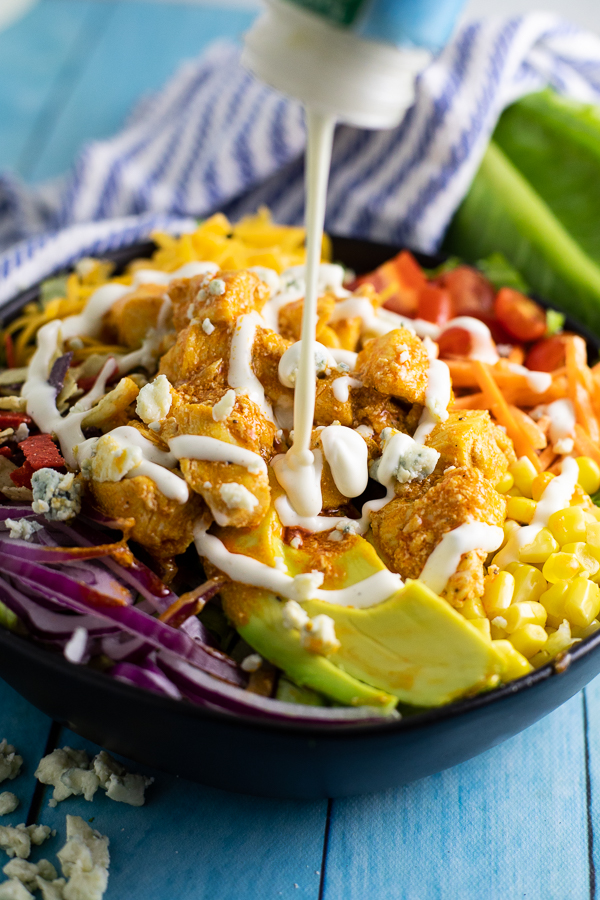 Fully loaded buffalo chicken salad being drizzled with ranch dressing