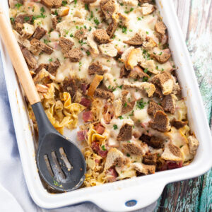 Reuben casserole in a large white casserole dish with a wooden spoon in it.