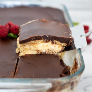 A slice being lifted out of a chocolate eclair cake topped with ripe raspberries