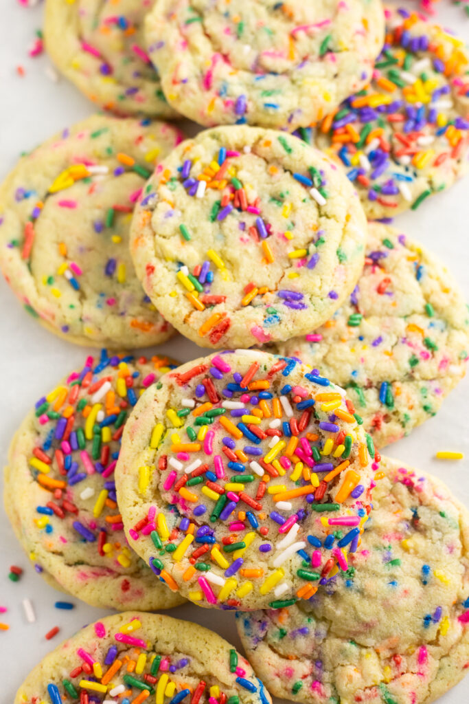 Close up of Funfetti cookies with rainbow sprinkles stacked in a neat pile on a white background