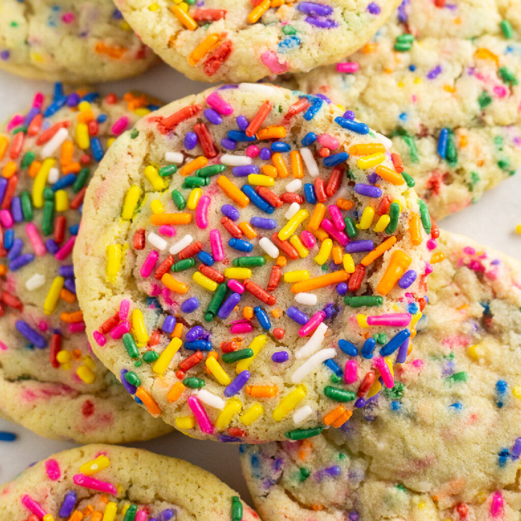 Close up of Funfetti cookies with rainbow sprinkles stacked in a neat pile on a white background