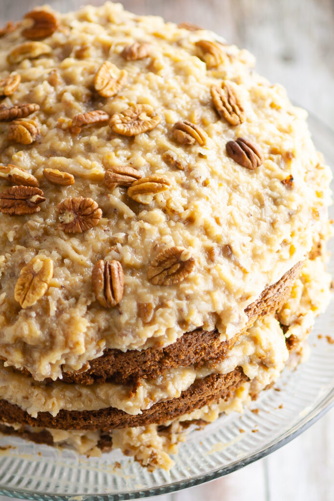 Coconut pecan frosting on top of a German chocolate cake topped with toasted pecans