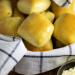 Texas Roadhouse rolls in a bowl with a striped linen