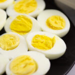 Hard boiled egg halves with the yolks face up on a small black plate