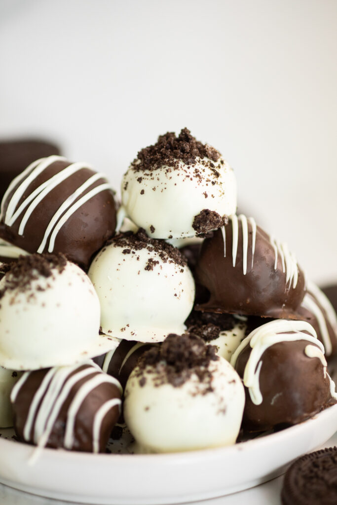 A pile of Oreo truffles on a small white plate with a white background.