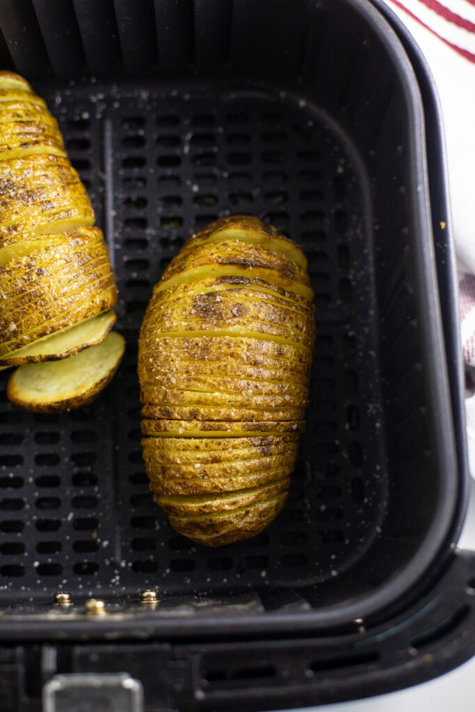 Overhead view of a hasselback potato in an air fryer basket.
