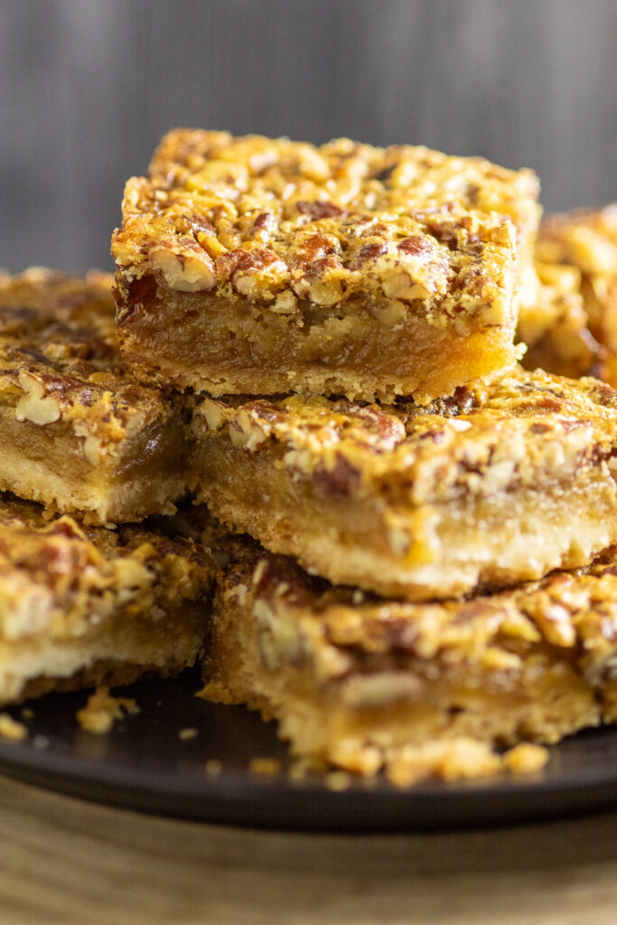 Southern Pecan Pie bars piled high on a plate.