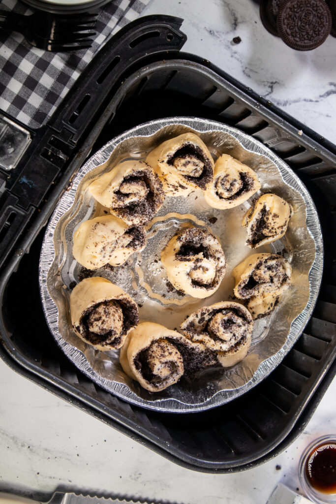 Overhead view of a pan of uncooked oreo cinnamon rolls in an air fryer basket.