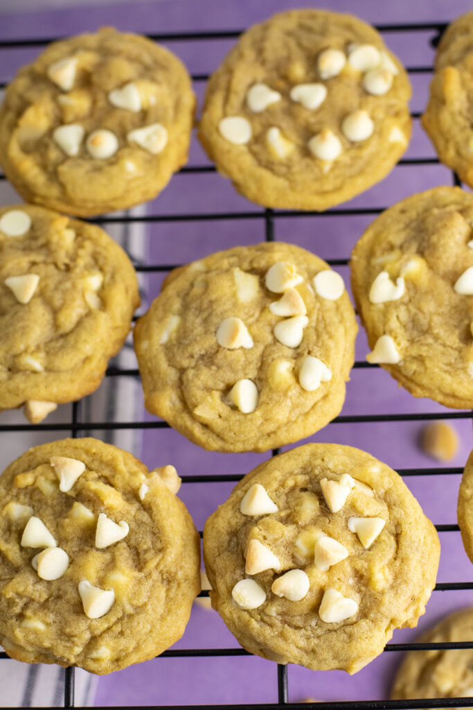 An overhead view of white chocolate macadamia nut cookies sitting on a wire cooling rack.