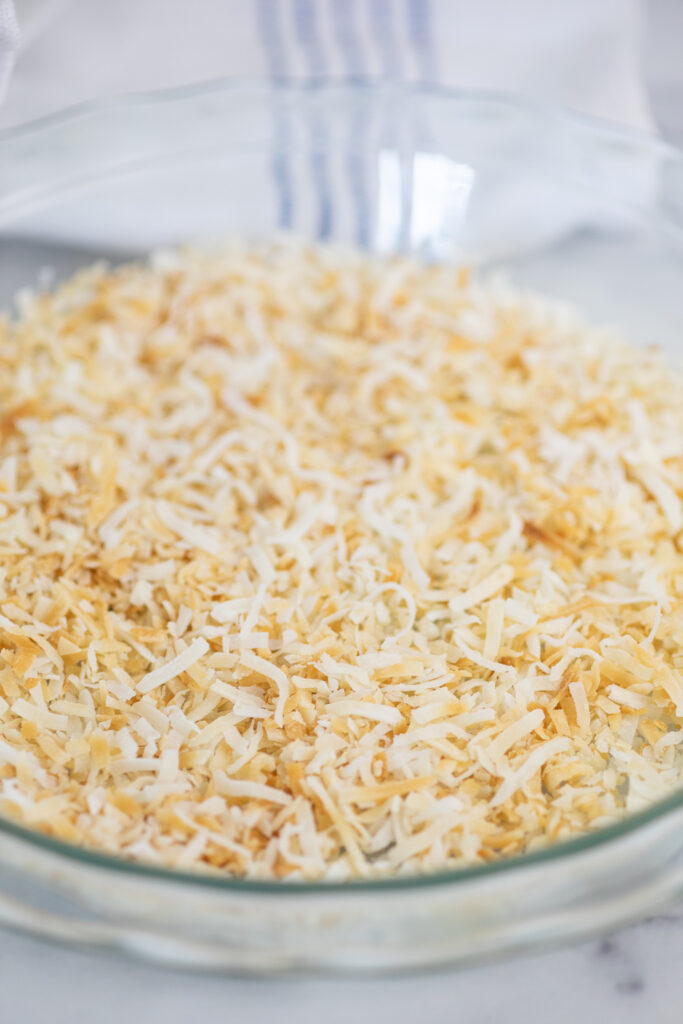 Close up of toasted coconut in a round glass pie dish.