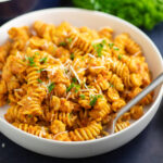 Romesco Pasta in a bowl with a fork topped with fresh parsley and manchego cheese.