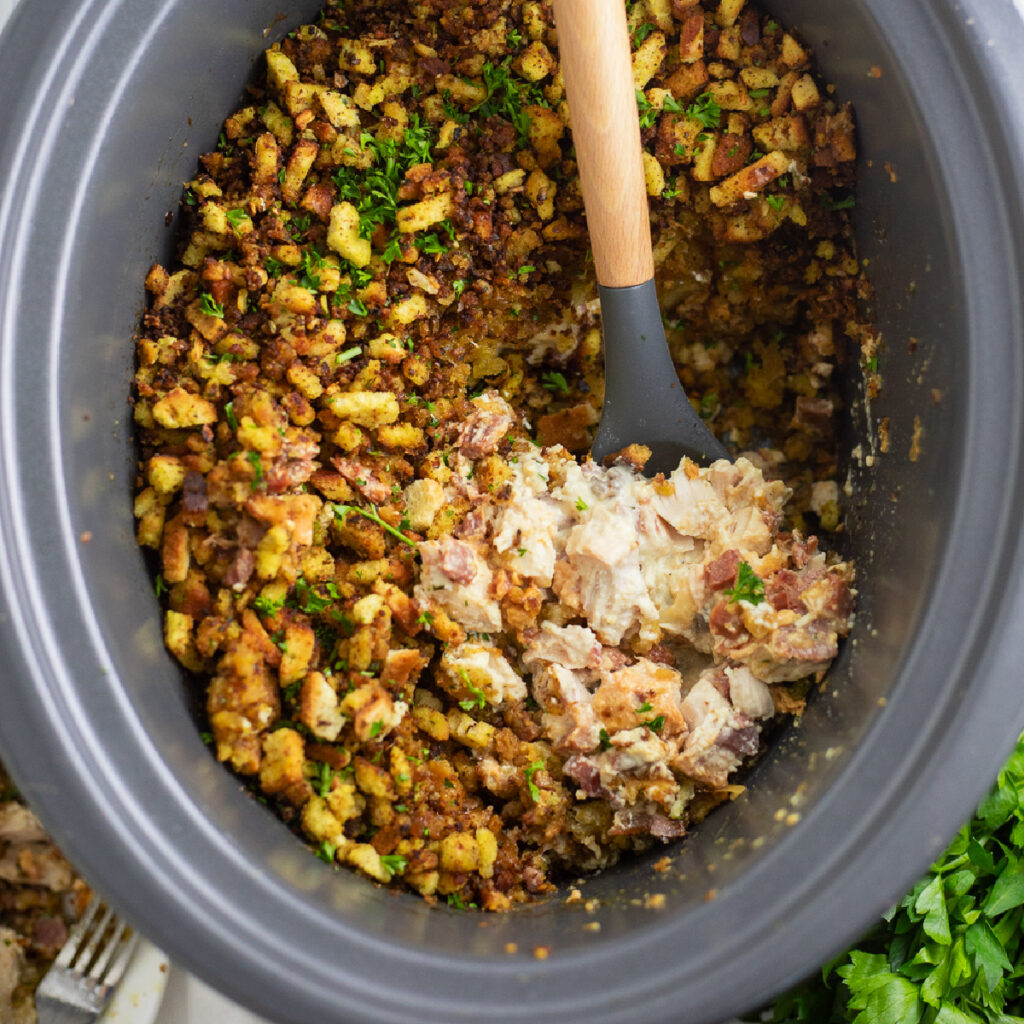 Crockpot Chicken Cordon Bleu in the crock of a slow cooker with a wooden spoon in the middle scooping out a big scoop.
