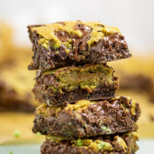 Side view of a stack of four mint chip brookies that have melty chocolate chips and a bite taken out of the top one.