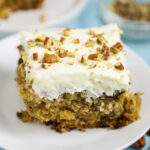 Preacher Cake topped with cream cheese frosting and chopped pecans on a small white plate.
