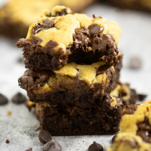 A stack of three brookies with a bite taken out of the top one with chocolate chips around.