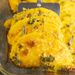 Spatula holding up three slices of baked butternut squash covered in garlic sage butter and topped with bubbly parmesan cheese.