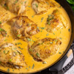 Overhead view of poulet au vinaigre in a cast iron skillet topped with fresh tarragon.